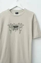 Remera beige de algodón premium, corte oversize y manga corta. Estampado frontal con diseño abstracto en negro.