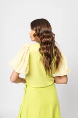 Blusa verde con cuello redondo y mangas cortas abullonadas.