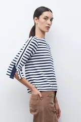 Remera de manga tres cuartos con diseño a rayas horizontales en azul marino y blanco. Presenta un detalle de volados laterales en las mangas y cuello redondo.