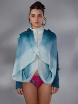 Saco largo de lana merino tejido con diseño jacquard de ramas, de líneas rectas y aberturas laterales, con efecto degradado en tonos azules y blancos, mangas largas con puños entallados y cierre frontal con pequeños botones.
