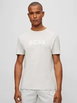 Remera de manga corta, cuello redondo, color gris claro o blanco roto, con el logo "BOSS" estampado en blanco en el pecho.