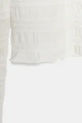 Chaqueta de punto blanco con textura de nido de abeja, cuello redondo, manga larga y cierre frontal con botones.
