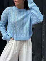 Sweater color crema tejido con diseño en ochos y cuello redondo.