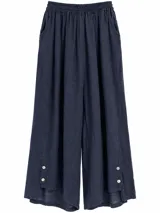 Pantalón ancho color azul marino con cintura elástica fruncida, bolsillos laterales y detalle de botones en los tobillos.