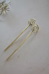 Par de hebillas doradas para el pelo con forma de espiral.