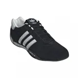 Championes Adidas modelo Adi Racer Lo, de diseño inspirado en el automovilismo. Presentan una base de gamuza negra con las icónicas tres tiras laterales en color plateado y detalles metálicos en el talón. Incluyen suela de goma con logo Adidas en el lateral.