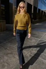 Jersey de punto color mostaza con cuello barco, manga larga con sisa ancha y detalle de cinturón fino integrado en la cintura.