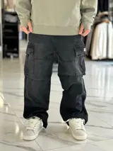 Pantalón cargo de jean negro con efecto acid wash, corte baggy oversize, múltiples bolsillos laterales con solapa y diseño holgado en las piernas.