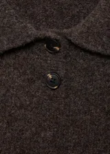 Jersey de punto grueso con cuello polo y cierre frontal de dos botones. Presenta un diseño corto de corte recto y mangas cortas.