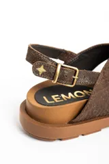 Sandalias de cuero color marrón con tiras cruzadas en el empeine, suela chunky texturizada y tira trasera ajustable con hebilla metálica.