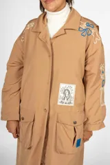 Trench color camel con cuello clásico, solapas grandes, cierre cruzado con botones, cinturón ajustable, bolsillos laterales y largo midi.