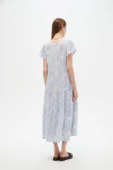 Vestido midi de viscosa con estampado floral en tonos celeste y blanco, cuello en V, mangas cortas y diseño holgado con volados escalonados en la falda.