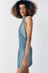 Vestido corto de denim con cuello halter, espalda descubierta y diseño de lavado combinado en tonos de azul.