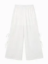 Pantalon blanco de corte amplio y tejido liviano con bordado floral en la parte inferior, aberturas laterales con tiras para atar y cintura elastizada.