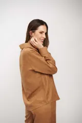 Camisa de manga larga color tostado, con cuello clásico y cierre frontal de botones. Presenta un diseño de corte recto y acabado suave.