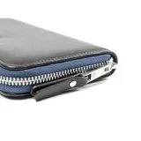 Billetera negra de símil cuero con cierre perimetral, logo de la marca en el frente y herrajes plateados. Cuenta con 13 compartimentos internos y un bolsillo con cierre.