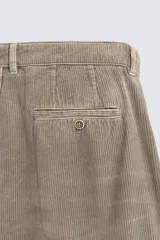 Bermuda wide fit color beige, confeccionada en pana de algodón. Presenta pliegues frontales en la cintura, bolsillos delanteros y bolsillos traseros de plastrón. Cierre frontal con cremallera y botón.