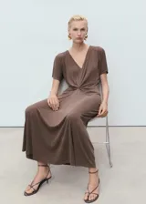 Vestido midi de color marrón, con escote en pico, manga corta y detalle de fruncido central en la cintura que crea un efecto drapeado.