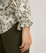 Blusa de crepé color blanco con estampado de hojas verdes, escote en V y mangas largas abullonadas con detalle de nudo en los puños.