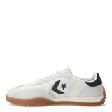 Championes Converse Run Star Trainer OX, de diseño urbano con capellada de tela y refuerzos de gamuza en tono crema. Presenta el logo de estrella y chevron en color negro en el lateral, con suela de goma color caramelo y detalle en el talón.