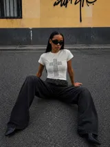 Remera blanca de manga corta ajustada al cuerpo, con cuello redondo y estampado frontal de una cruz formada por tachas plateadas.