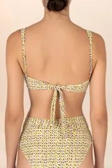 Top de bikini bandeau con estampado floral en tonos amarillo y lila, con detalle de cuentas marrones en el centro. Breteles anchos y ajustables.