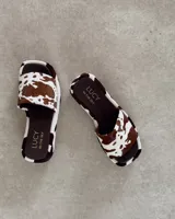 Zueco de cuero vacuno con pelo, diseño de punta cuadrada y estampado animal print tipo vaca. Cuenta con una base de 3.5 cm de altura y plantilla de cuero marrón con logo de la marca.