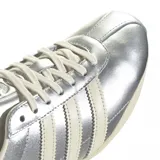 Championes Adidas modelo Tokyo, con diseño de perfil bajo en color plateado metalizado. Presenta las icónicas tres tiras laterales y suela en tono crema, con el logo de la marca y el nombre del modelo grabados en el lateral.
