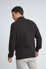 Campera tejida de algodón con cierre frontal completo, cuello alto y mangas largas con puños acanalados. Presenta un diseño de punto acanalado vertical y un pequeño logo bordado en el ruedo.