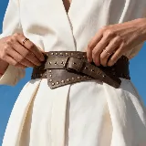 Cinto faja ancho de cuero genuino color tostado, con diseño de tachas metálicas decorativas y hebilla de metal envejecido.