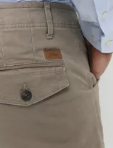 Pantalón cargo de algodón sarga con elastano, color verde militar. Presenta bolsillos laterales con fuelle, bolsillos traseros con tapa y botón, y costuras reforzadas en las rodillas.