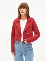 Chaqueta corta tipo blazer en color bordó, con diseño de doble botonadura frontal, solapas clásicas y detalles de charreteras en los hombros con botones metálicos.