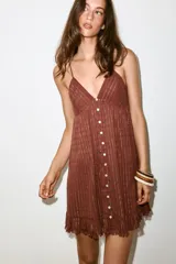 Vestido mini marrón terracota con finas rayas verticales de hilo metalizado, escote en V, tirantes finos ajustables, cierre frontal con botones y detalle de volados desflecados en el borde inferior.