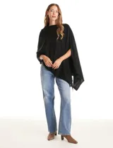 Poncho tejido de punto con diseño asimétrico y aberturas laterales para los brazos.