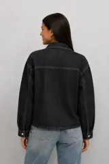 Campera de jean color negro lavado, con cierre frontal de botones metálicos, cuello clásico y dos bolsillos frontales con solapa.
