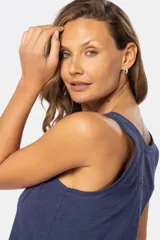 Musculosa blanca sin mangas, de corte clásico y calce cómodo, confeccionada en tejido suave. Presenta escote redondo, cartera con botones frontales y un pequeño bolsillo aplicado en el pecho.