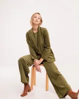 Pantalón de pana color verde oliva, de corte wide leg y largo al tobillo. Tiene cierre delantero con botón, bolsillos laterales y traseros.