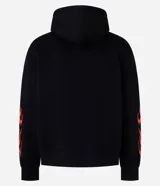 Buzo con capucha negro de corte oversized, con bolsillo canguro y cordones ajustables. Presenta un estampado frontal con una calavera y la palabra 'FEARLESS' envuelta en llamas naranjas y rojas, diseño que se repite en las mangas.