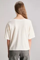 Remera color crudo de calce boxy, confeccionada en jersey de algodón con elastano. Tiene cuello redondo en rib a tono y manga corta. Incluye estampa en delantero con la frase 'My favorite outfit is love' combinada con cristales hotfix a tono.