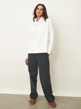 Polera de manga larga en color negro, confeccionada en tejido de punto con textura acanalada fina. Presenta un cuello alto tipo polera, corte holgado y puños ajustados.