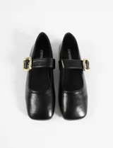 Balerinas negras de cuero sintético con punta cuadrada, tira sobre el empeine y hebilla dorada.