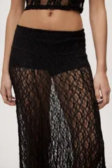 Falda larga de encaje negro semitransparente, de tiro medio y diseño amplio con textura floral.