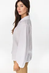 Camisa de lino italiano con estampado a rayas verticales irregulares, de corte holgado, cuello clásico, mangas abullonadas y cierre frontal con botones.