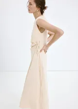 Vestido midi color beige, de cuello redondo y sin mangas, con diseño cruzado en la falda y lazo ajustable en la cintura.