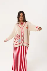 Saco oversize tejido con ilustraciones inspiradas en corales, peces, estrellas de mar y tortugas. Presenta galón picot en rojo en cartera y puños, y botones a tono.