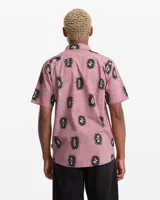 Camisa de manga corta Volcom modelo Abg Markerstone, color rosado con estampado tropical, cuello camisero, cierre frontal de botones y bolsillo en el pecho.