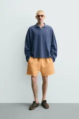 Bermuda de corte relajado confeccionada en tejido de algodón con interior de rizo. Presenta cintura elástica con cordón ajustable, bolsillos laterales, un bolsillo trasero de plastrón y bajo con acabado irregular con efecto lavado.