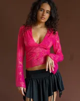 Top de encaje fucsia con escote en V profundo y mangas largas acampanadas.