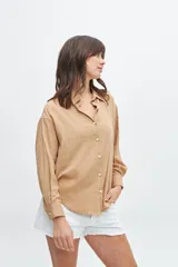 Camisa color beige de corte clásico, con cuello y mangas largas.