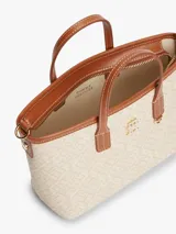 Cartera tote Tommy Hilfiger modelo TH Monoplay, color beige con estampado integral del monograma TH en relieve, asas superiores y correa bandolera extraíble de cuero sintético marrón. Cuenta con cierre de cremallera e insignia metálica del monograma en el frente.